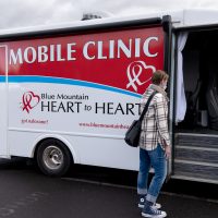 Patient in jeans and a jacket approaching the steps to enter a community health / syringe services program mobile clinic van
