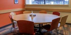 Round meeting table in a recovery support organization with chairs next to a bright window.