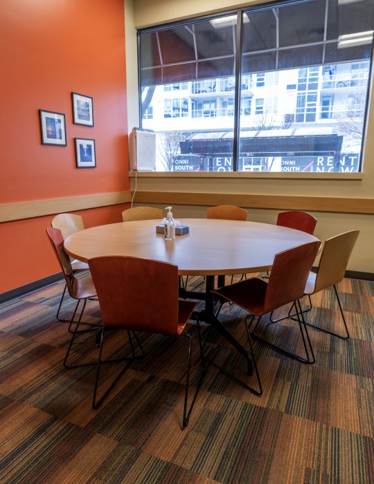 Round meeting table in a recovery support organization with chairs next to a bright window.
