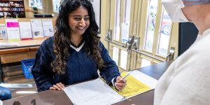 Person checking in at the front desk of a recovery support organization smiles at a staff person