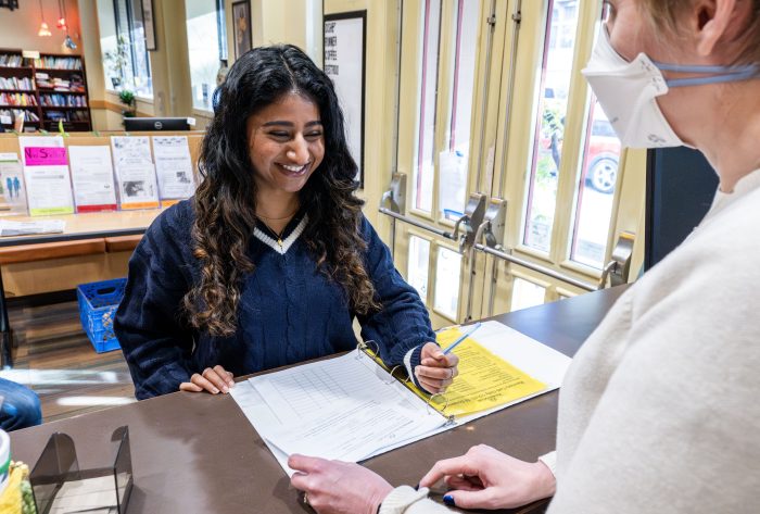 Person checking in at the front desk of a recovery support organization smiles at a staff person
