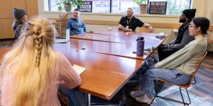 A diverse group of people talking at a long table in a recovery support organization