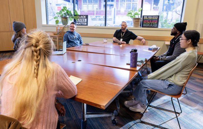 A diverse group of people talking at a long table in a recovery support organization