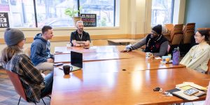 A diverse group of people sitting at a long table smiling and talking