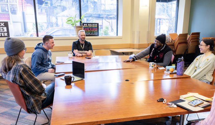 A diverse group of people sitting at a long table smiling and talking