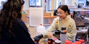 A barista in a recovery support organization cafe serves a visitor