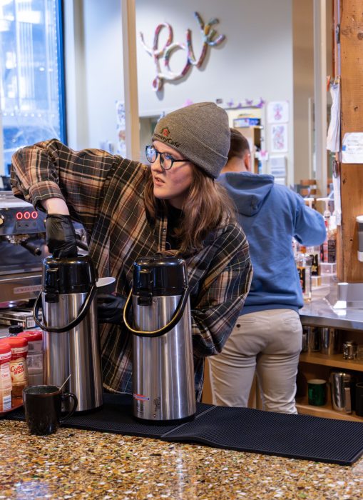 A barista in a recovery support organization cafe fills a cup with coffee